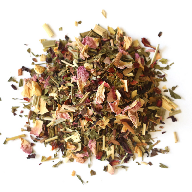 A pile of Hibiscus High Tea by Mountain Rose Herbs, a loose leaf herbal blend with dried rose petals, lemongrass, green leaves, and colorful plant pieces displayed on a white background.