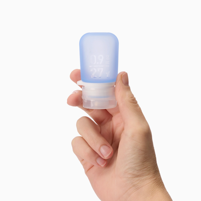 A hand holding the extra small 0.9 oz silicone squeeze tube in the color blue. 