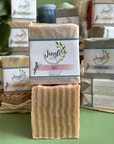 Jangle Soaps Rose Goat's Milk Soap wrapped in white paper and on top of a bulk loaf of the same soap.