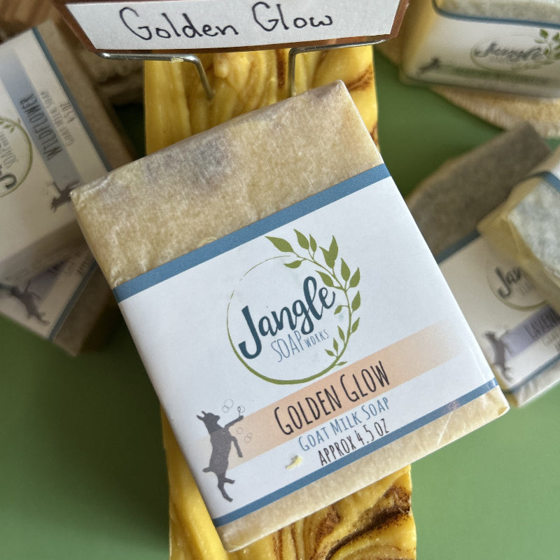 Jangle Soaps Golden Glow Goat's Milk Soap wrapped in white paper and on top of a bulk loaf of the same soap.