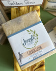Jangle Soaps Golden Glow Goat's Milk Soap wrapped in white paper and on top of a bulk loaf of the same soap.