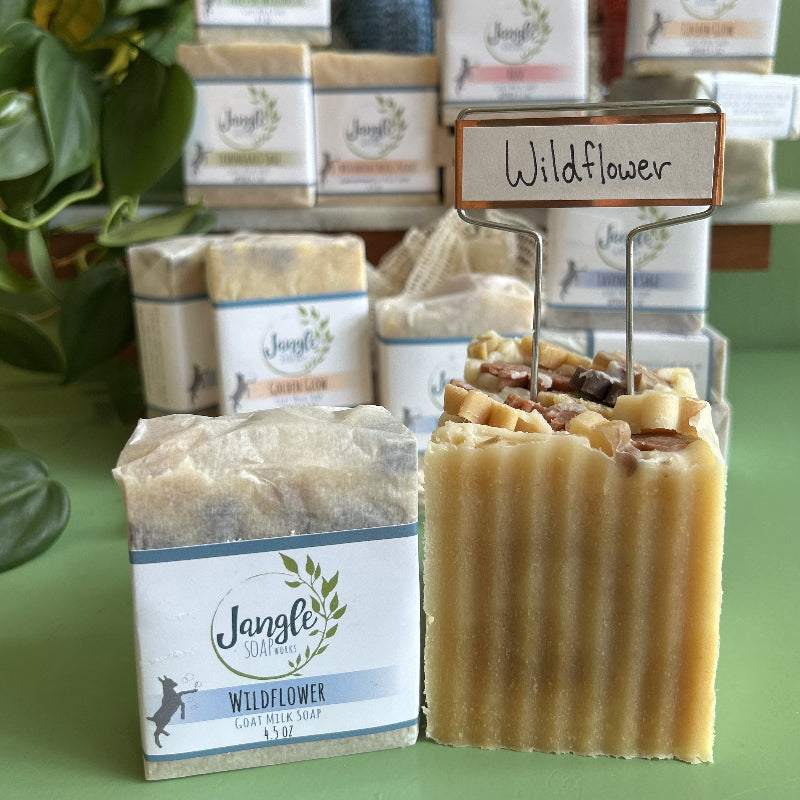 Jangle Soaps Wildflower Goat's Milk Soap wrapped in white paper and on top of a bulk loaf of the same soap.