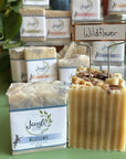 Jangle Soaps Wildflower Goat's Milk Soap wrapped in white paper and on top of a bulk loaf of the same soap.