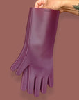 A tattooed hand holds Fig  premium silicone dishwashing gloves on a brown background. 