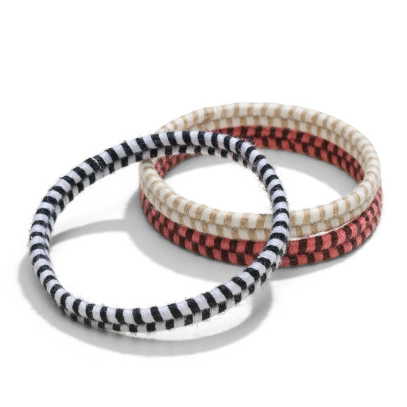 Three handmade biodegradable hair ties on a white background. All the hair ties have a chevron pattern, One hair ties is Black and white, one is beige and white and one is pink and brown. 