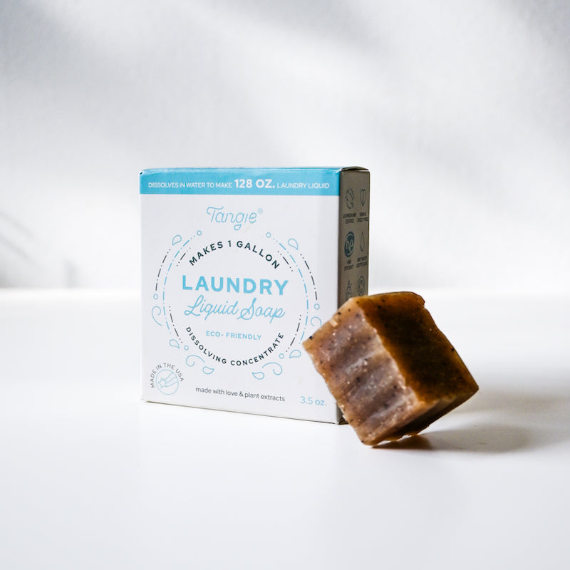 Bar of soap next to a box of laundry liquid soap on a white background