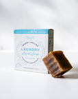 Bar of soap next to a box of laundry liquid soap on a white background