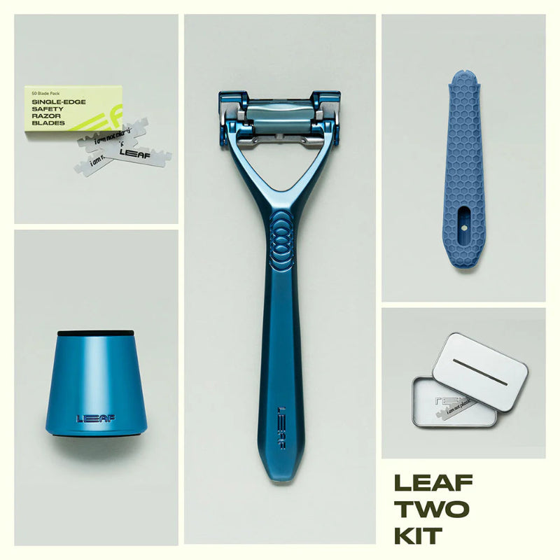 A flat lay of the leaf two razor kit in the color glacier.  The image shows the contents of the Leaf two razor kit next to the razor is a 50 count refill pack, a matching glacier stand, a silicone handle sleeve, and a recycling tin.