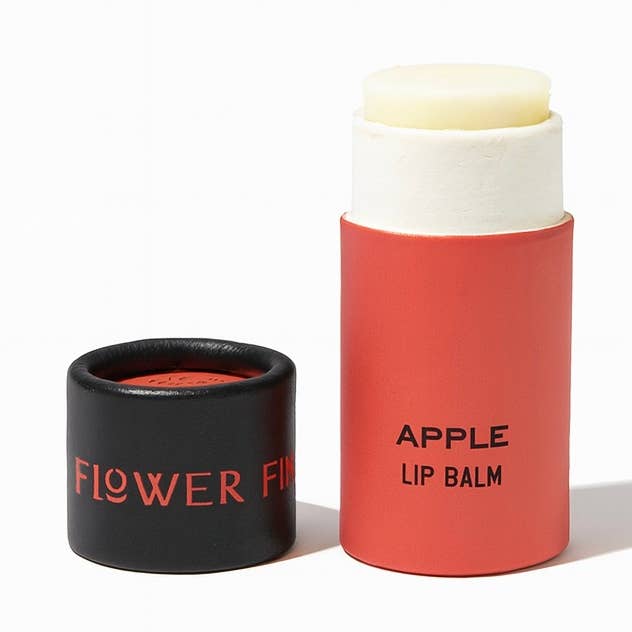 A tube of apple lip balm in an eco friendly paper tube that is red and black. 