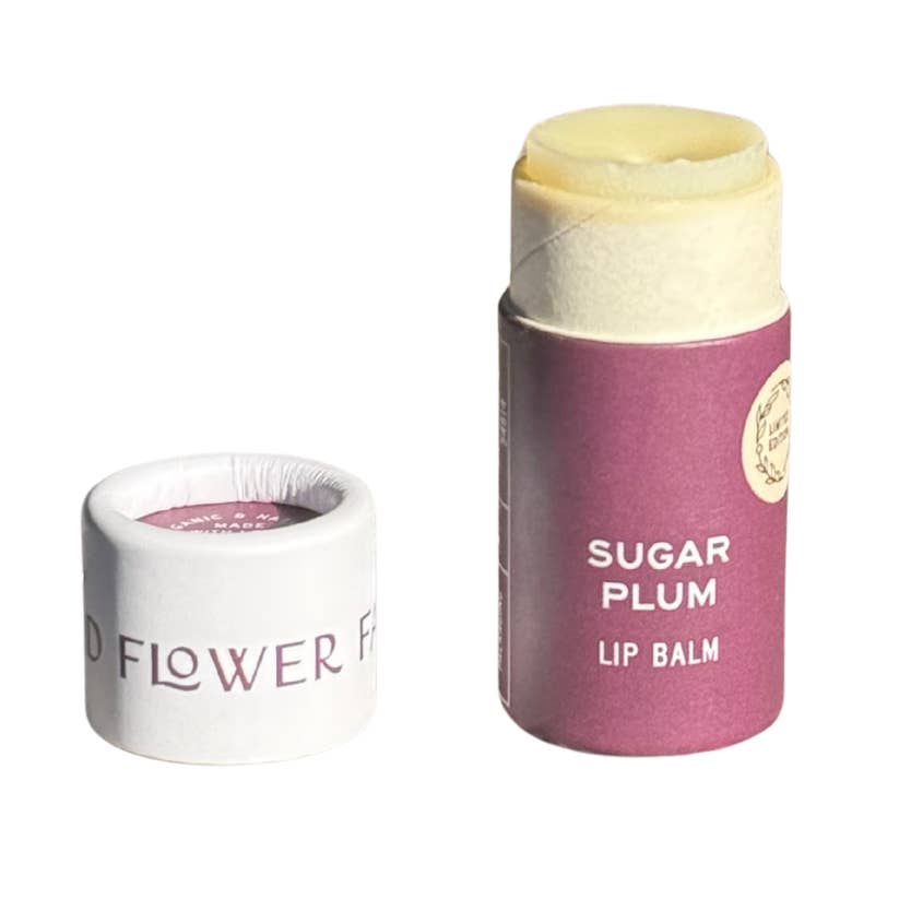 A tube of Sugar Plum lip balm in an eco friendly paper tube that is purple  and white. 
