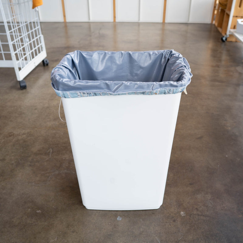 A large white trash bin with a Frey reusable drawstring pail liner in it. 