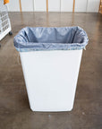 A large white trash bin with a Frey reusable drawstring pail liner in it. 