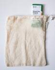Mesh produce bag with a package of Raaka Green Tea Crunch on a white background
