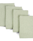 Four sage green waffle weave upcycled cotton towels lying on top of each other on a white background. 