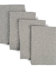 Four grey waffle weave upcycled cotton towels lying on top of each other on a white background. 