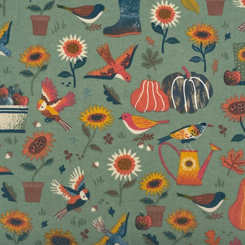 No paper towel with a fall garden scene pattern. There are gardening supplies, gourds, sunflowers, and birds on a sage colored background. 