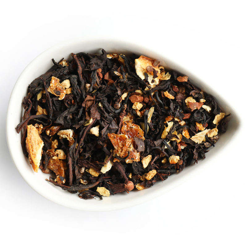 A teardrop-shaped white bowl holds Mountain Rose Herbs’ Orange Spice Tea—loose leaf black tea blended with dried orange peel and spices—displayed against a white background.