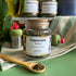 A refillable Jar of peppermint tea. The jar has a cork lid and an attachable bamboo spoon. 