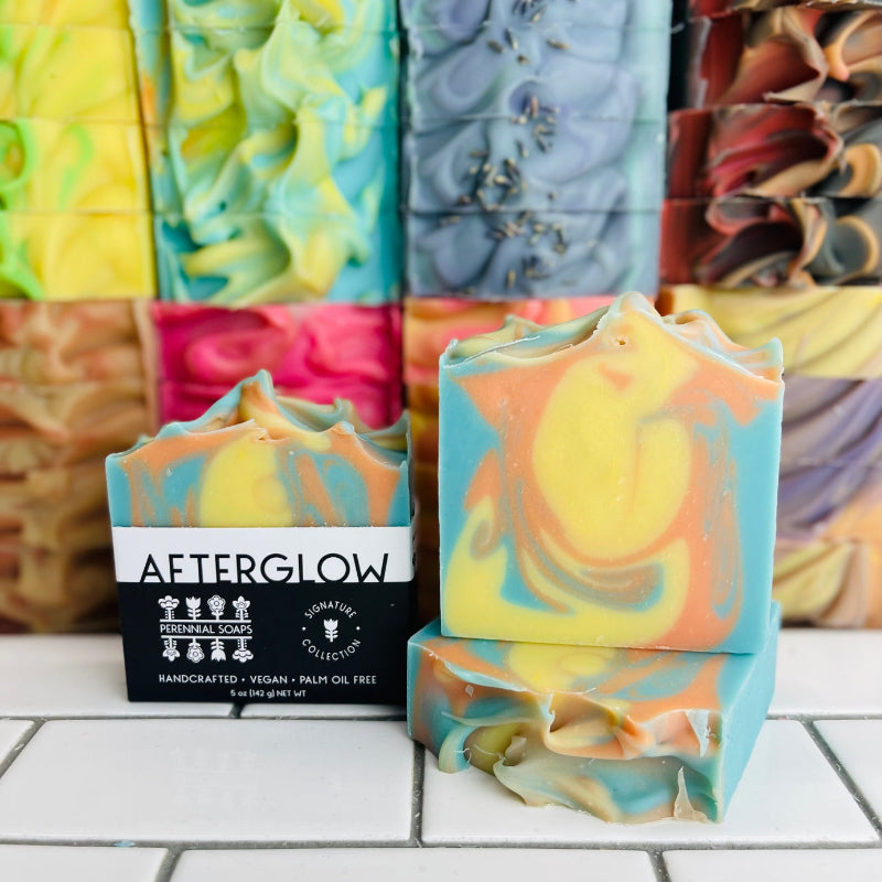 Perennial Soaps Afterglow bar in front of a stack of bar soaps.