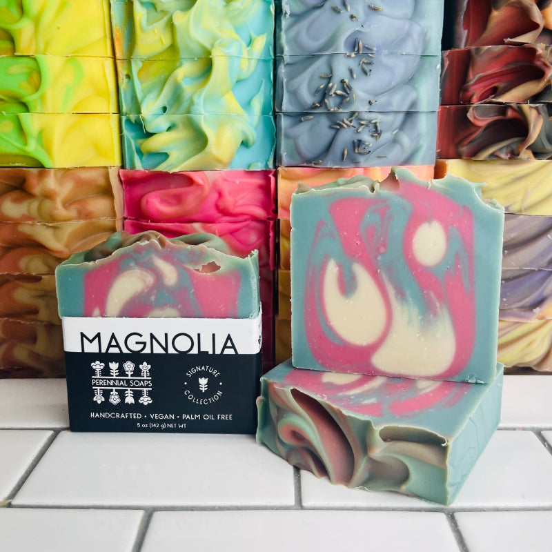 Magnolia Soap bars with a stack of various soap bars behind it. 