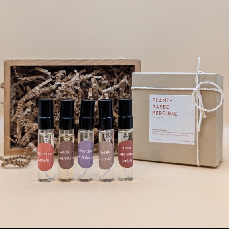 A discovery set featuring five samples of refillable plant based perfumes. The small glass vials have a black lids and each are labeled with a sticker. The gift box is brown paper and filled with craft paper. 
