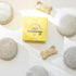 A yellow Tangie Pet Shampoo box is surrounded by four round bars enriched with lemongrass and neem oils, along with three dog bone-shaped biscuits, all neatly arranged on a white surface.