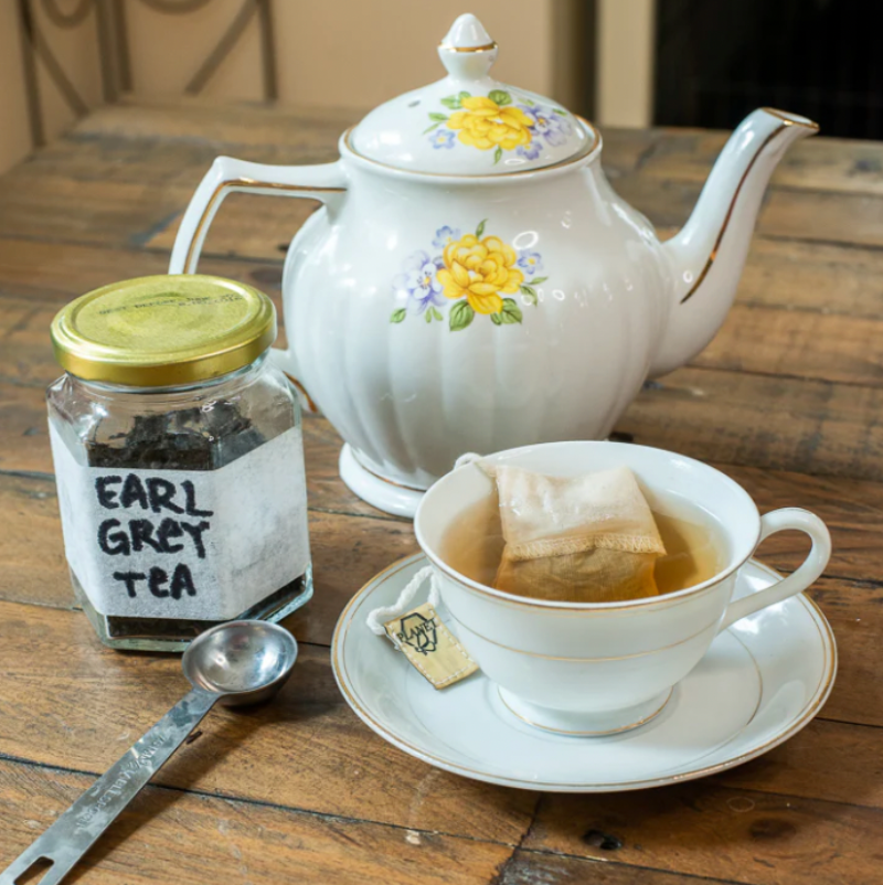 Tea pot and teacup holding the Planet B Reusable Tea Bag while it steeps a cup of tea. 