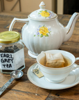 Tea pot and teacup holding the Planet B Reusable Tea Bag while it steeps a cup of tea. 