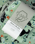 A stack of the Black Cat Patterned Paperless towels with the same patterned paperless towel in the background. 