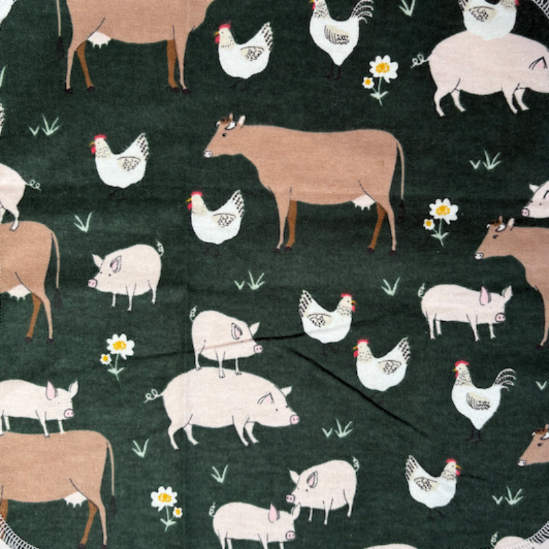 The Farm Friends patterned paperless towel which features pigs, cows, and chickens on a dark green background. 