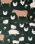 The Farm Friends patterned paperless towel which features pigs, cows, and chickens on a dark green background. 