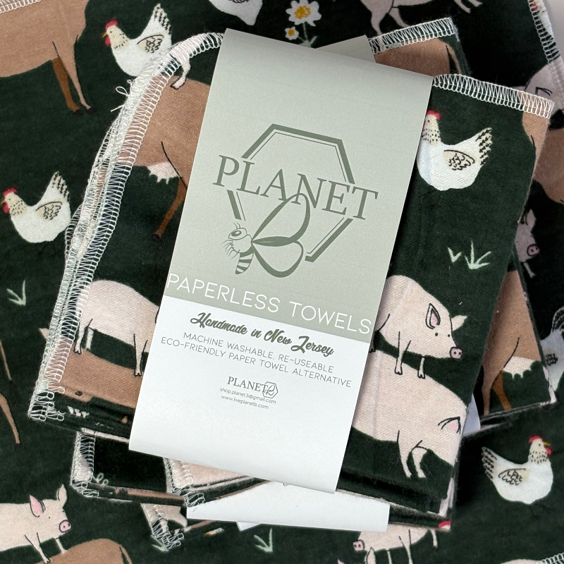 A stack of the Farm Friends Patterned Paperless towels with the same patterned paperless towel in the background. 