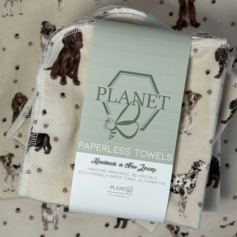 A stack of the Puppy Pals Patterned Paperless towels with the same patterned paperless towel in the background. 