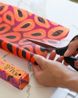 Person cutting a colorful box with scissors on a white surface