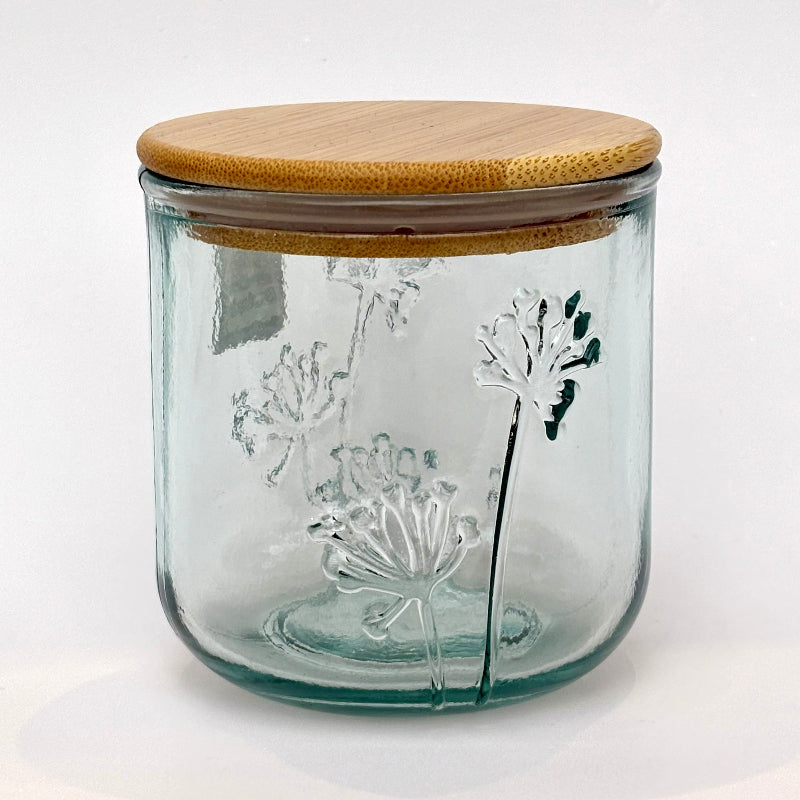 Clear glass jar with a slight blue tint and a bamboo lid featuring floral embossing on a white background