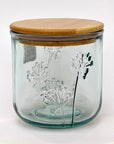 Clear glass jar with a slight blue tint and a bamboo lid featuring floral embossing on a white background