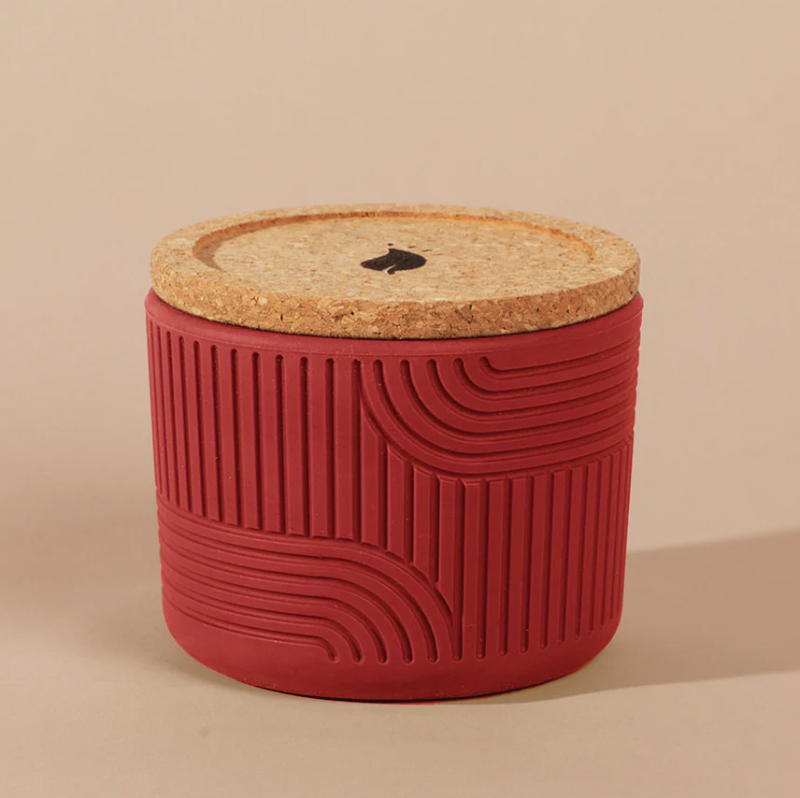 Red textured container with a cork lid on a beige background