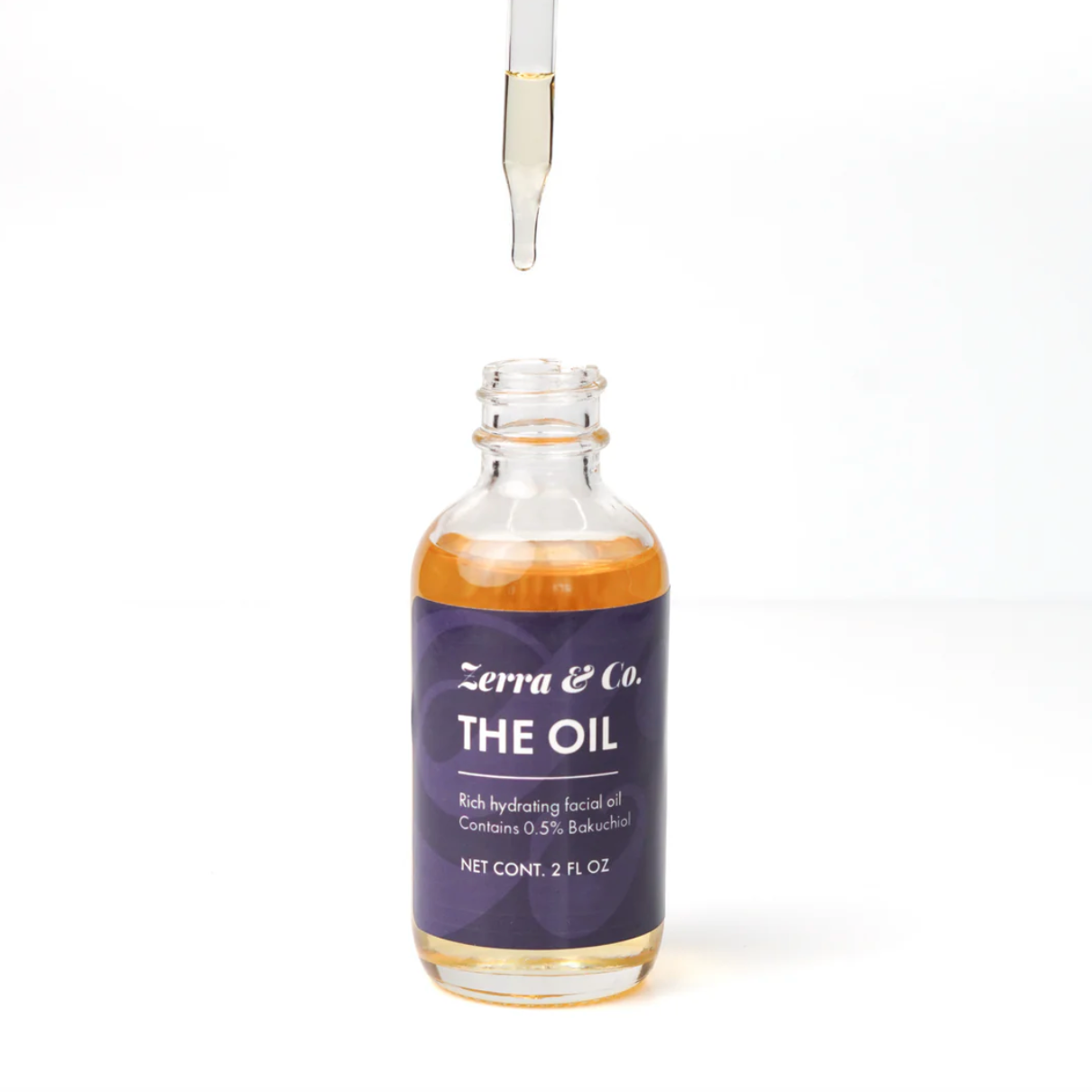 Dropper above bottle with oil in it on white background. Black label on bottle