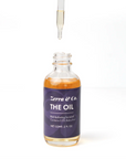 Dropper above bottle with oil in it on white background. Black label on bottle