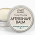 A round metal tin of Lovett Sundries Aftershave Balm sits with its lid slightly open, showing the creamy balm inside.