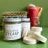 A Jar of refreshing shower steamers on a green background with a stack of shower steamers next to it. 