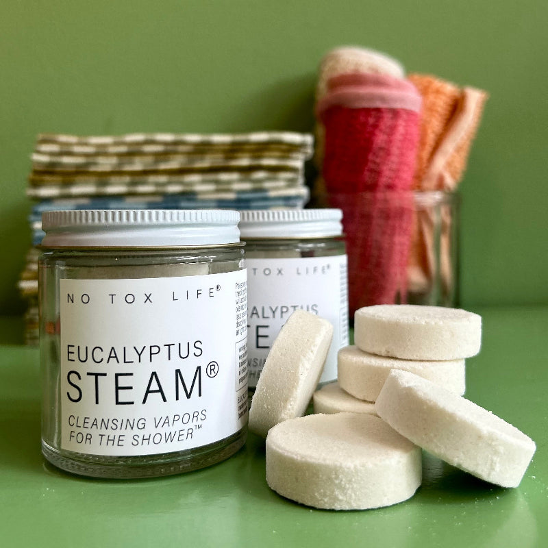 A Jar of refreshing shower steamers on a green background with a stack of shower steamers next to it. 
