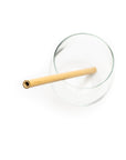 A glass with a reusable and compostable bamboo straw resting in it, on a white background. 