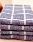 Stack of purple checkered towels on a wooden surface