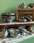 A large spread of different sized stainless steel funnels in stacks on a green background. 