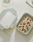 Gray food container with oatmeal and almonds on a light surface
