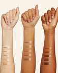 light medium and dark skinned arms with makeup foundation swatched on them on white background.