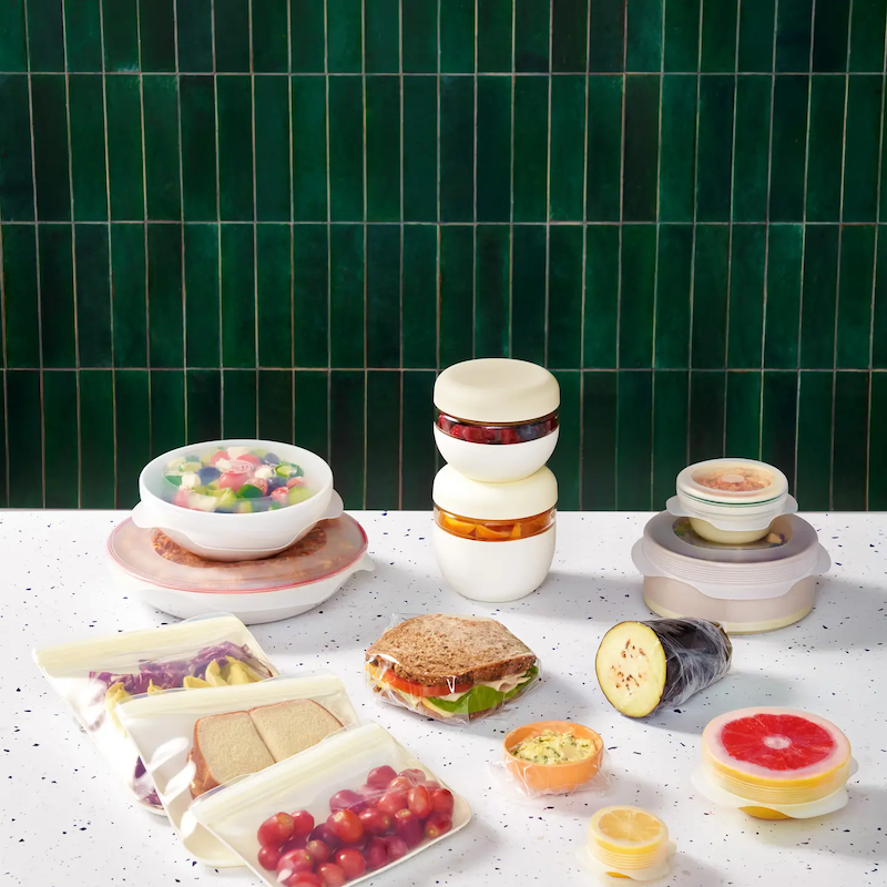 The Sustainable kitchen set in use wrapping a multitude of different foods on a counter with a green tile background.