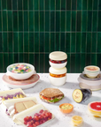 The Sustainable kitchen set in use wrapping a multitude of different foods on a counter with a green tile background.