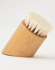 angular wood shaving brush standing up on white background